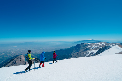 Freeride couple admiring endless possibilities for snowboarding fresh powder snow. Young woman and man holding snowboards on top of snowy mountain ridge. Amazing views in pristine Albanian mountains.