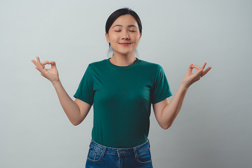 Woman meditating holding her hands in yoga gesture isolated on background.
