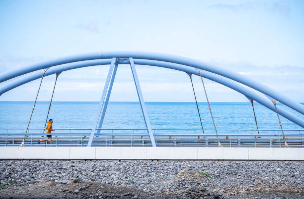 Active and healthy man on a morning jog on a bridge by the ocean.