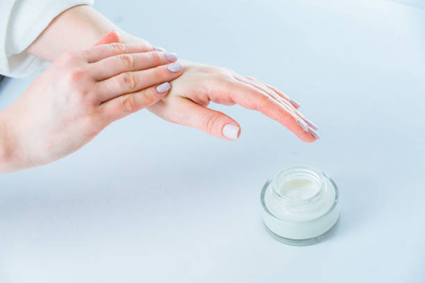 Woman hands applying moisturizer cream on hands stock photo