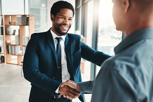Businessman, handshake and smile for partnership, b2b or trust in promotion, deal or agreement at office. African American male manager shaking hands with employee for welcome, thank you or greeting