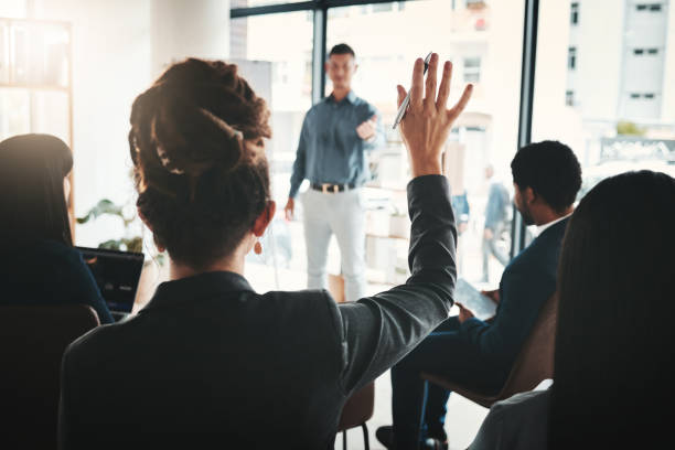 istock Businessman, coaching and presentation with audience in FAQ, answer or leadership at office workshop. Male leader speaking in staff training with hand raised for marketing, planning or strategy idea 1486996458