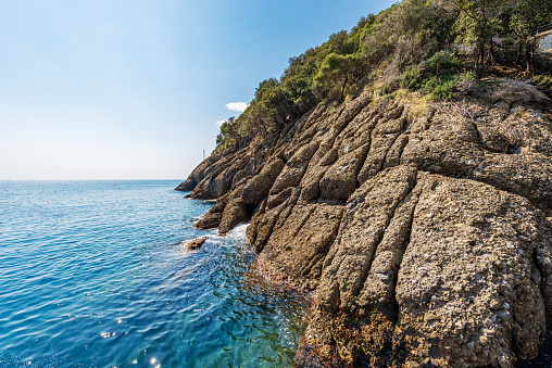 Rocky coastline and cliffs of San Fruttuoso bay, famous for its ancient abbey. Mediterranean sea (Ligurian sea) between Portofino and Camogli, Genoa province (Genova), Liguria, Italy, Europe.