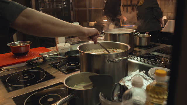 Unrecognizable Chefs Cooking Soup on Stove in Restaurant Kitchen