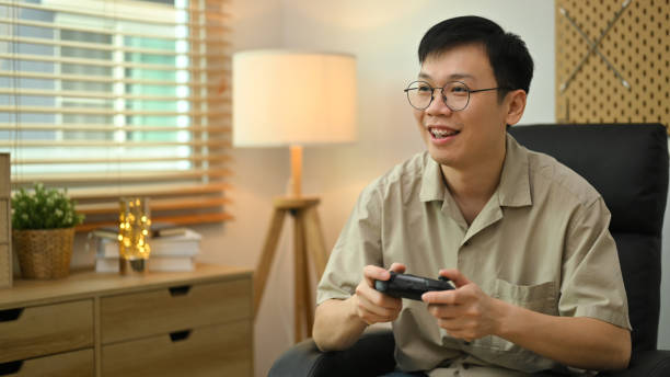 istock Happy man holding wireless controller playing video game. Entertainment, technology and hobby concept. 1486999806