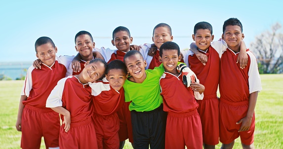 Portrait, kids and sports with a team of football players standing together on a field before a game. Children, fitness and teamwork with young athletes bonding while ready for a competitive match