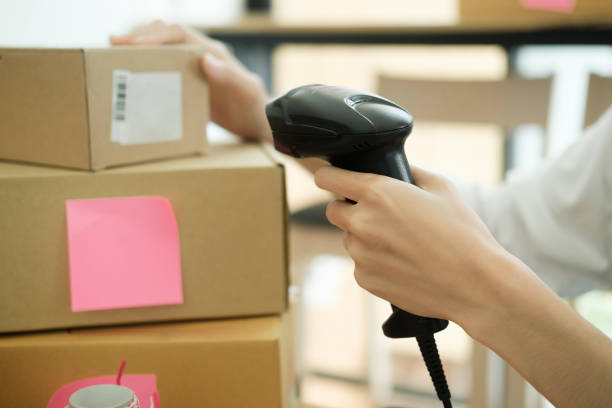 istock Female online business owner scanning parcel barcode tag. 1487002123