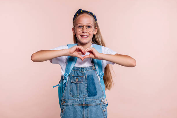 istock Blond school girl does heart shape with hands 1487006293