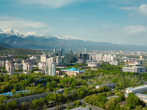 Aerial view of Almaty city during sunny spring day with snow capped mountains in the background