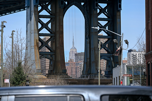 New York City, United States, April 8, 2023 - Empire State Building seen from Brooklyn with and Manhattan Bridge.