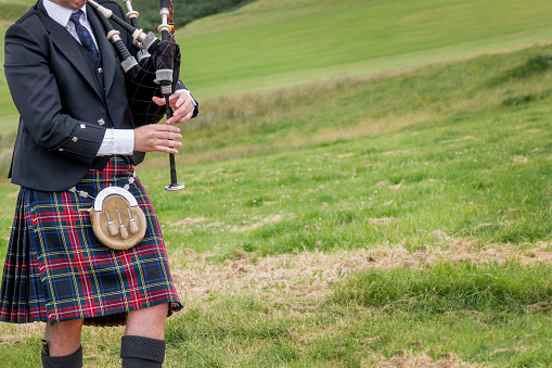 Scottish bagpiper dressed in traditional kilt in the Highlands of Scotland (with copy space)