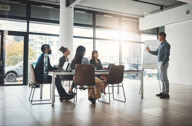 istock Businessman, coaching and whiteboard for presentation in leadership at office conference workshop. Male leader, coach or mentor speaking in staff training, marketing or planning in corporate strategy 1487015379