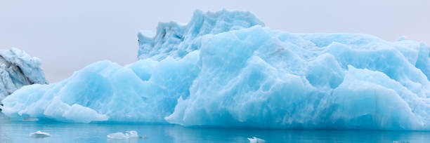 un iceberg azul en islandia. un iceberg que desemboca en la laguna de jokulsarlon, separado del frente del glaciar. - natural disaster glacier iceberg melting fotografías e imágenes de stock