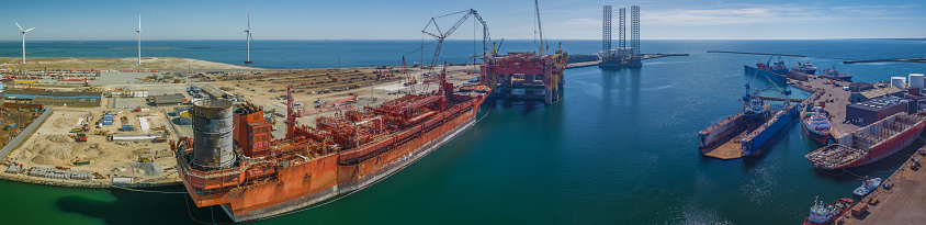 Oil rig and tanker in port for maintenance work. Oil terminal with storage tank farm, offshore oilrig, tanker in port. Business petroleum fuel and gas transport by tanker ship vessel.