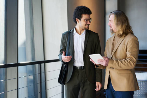 istock Young smiling businessman explaining something to mature colleague 1487017169
