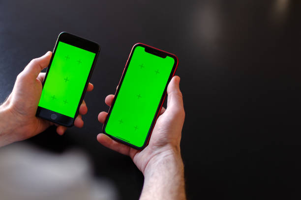 istock Two hands holding mobile phones data or information transfer between its, mockup or concept of wareless connection between apps. Black background, copy space for text 1487017478