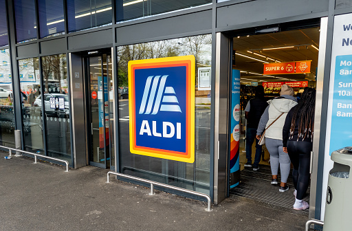 London. UK- 05.01.2023. The entrance and exit of a branch of Aldi grocery supermarket with the company name sign and logo in the middle.