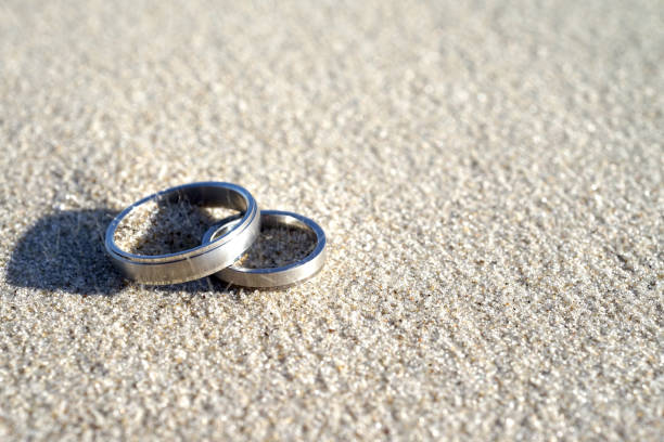 Silver wedding rings at the beach in the sand with copy space stock photo