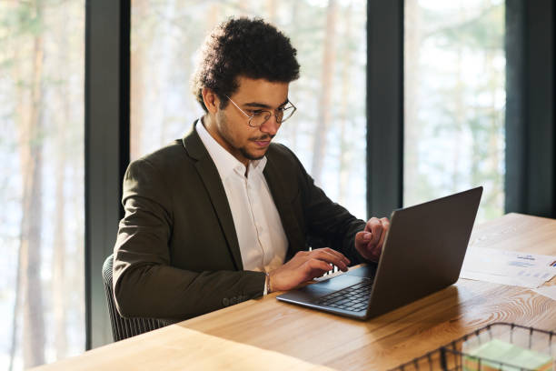 istock Serious young analyst or broker looking at laptop screen by workplace 1487024642