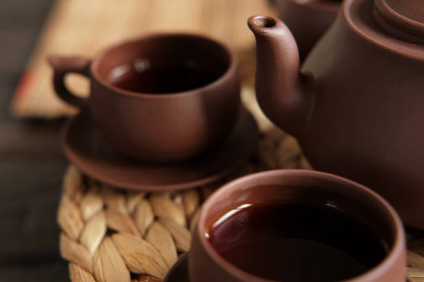 Tea Ceremony. Traditional Asian Tea Utensil, Serving Authentic Set. Person Pouring Tea from Brown Pottery Teapot to Teacup. Bamboo Tray. Lifestyle. Wellness Balance Health. Tea Brewing Equipment. Tea master. Dark mood. Japan. China. Serves chashaku. ceremonia del té. utensilios de té asiático tradicional, que sirve un conjunto auténtico. persona vertiendo té de tetera de cerámica marrón a taza de té. bandeja de bambú. modo de vida. wellness balance health. equipo de preparación de té