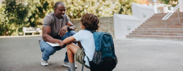 istock Teacher talking to a young student outdoors in a school 1487026335