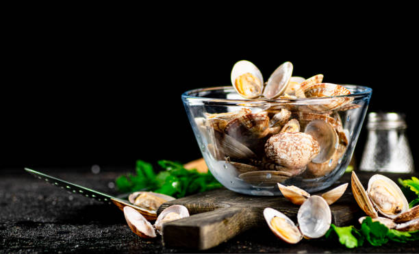 Fresh vongole in the bowl on a cutting board with parsley.