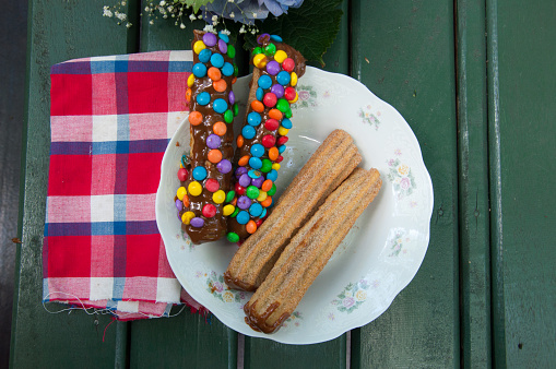 Eclairs with chocolate and colorful sprinkles on a plate.