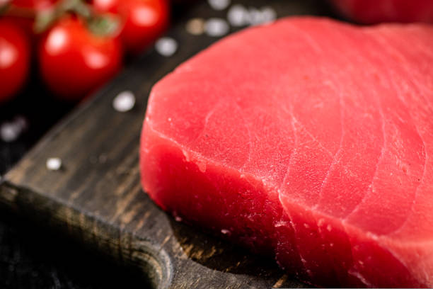 istock Fresh raw tuna on a cutting board with cherry tomatoes. 1487030174