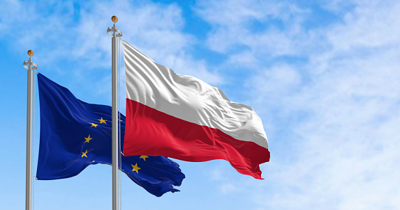 The flags of the Poland and the European Union waving in the wind on a clear day. Poland became a member of the EU in may 2004. 3d illustration render. Fluttering fabric