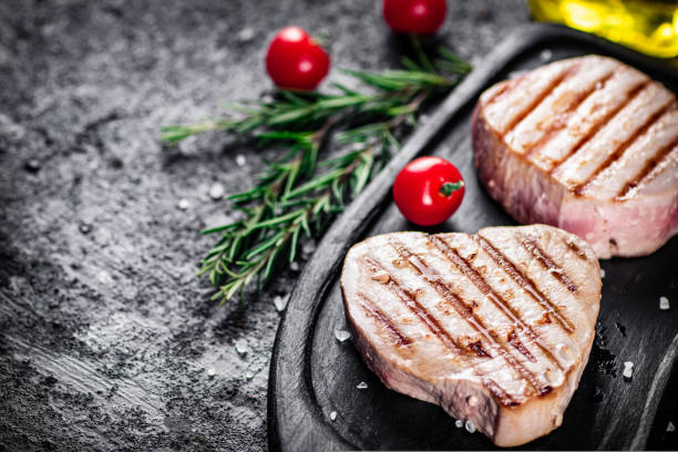 istock Grilled tuna on a tray with tomatoes and rosemary. 1487033373