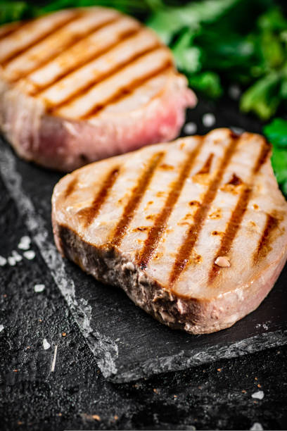 istock Grilled tuna on a stone board with parsley and salt. 1487033702