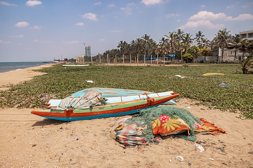 Negombo, Western Province, Sri Lanka - March 9th 2023:  Small fishing boat and a pile of fishing net on the popular beach