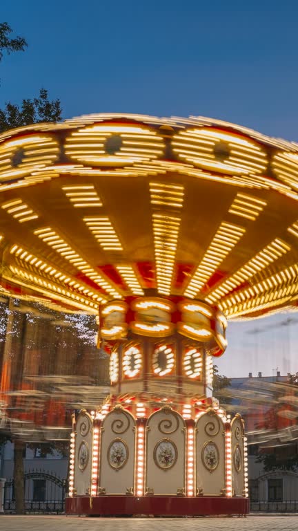 Brightly Illuminated Rotating High Speed Carousel Merry-Go-Round. Summer Evening In City Amusement Park hyperlapse vertical, vertical footage, vertical video