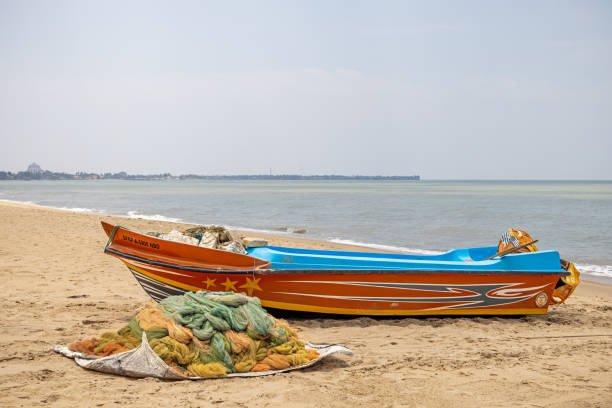 Negombo, Western Province, Sri Lanka - March 9th 2023:  Small fishing boat and a pile of fishing net on the popular beach