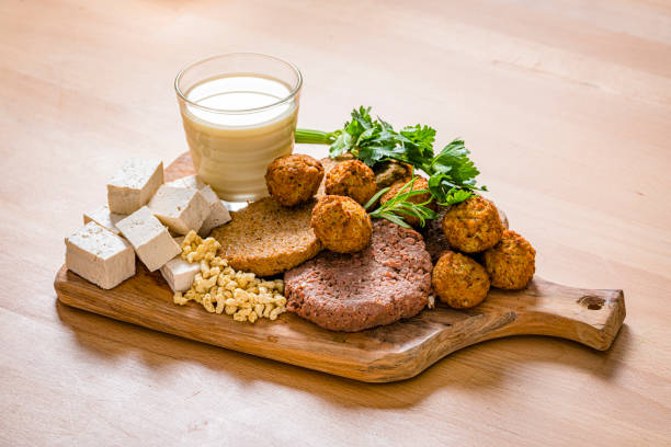 Plant-based meat and soy products Cutting board filled with plant-based meat, tofu and soymilk shot on wooden table. High resolution 42Mp studio digital capture taken with SONY A7rII and Sony FE 90mm f2.8 macro G OSS lens alternative lifestyle stock pictures, royalty-free photos & images