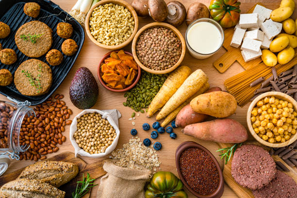 Plant-based food shot from above Assortment of plant-based food shot from above on wooden table. The composition includes soy beans, soy milk, tofu, legumes, root vegetables, wholegrain bread and veggy patties.and meatballs. High resolution 42Mp studio digital capture taken with SONY A7rII and Zeiss Batis 40mm F2.0 CF lens spanish hamburger stock pictures, royalty-free photos & images