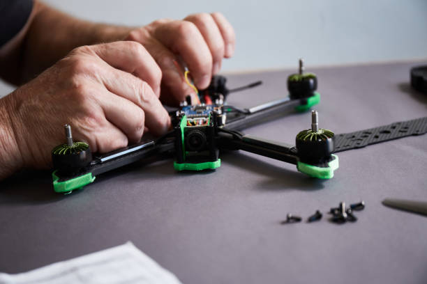 istock Close up of man's hands assembling a drone from parts, using tools, Preparing high speed racing quadcopter for flight. Repair drone before training process. 1487040940