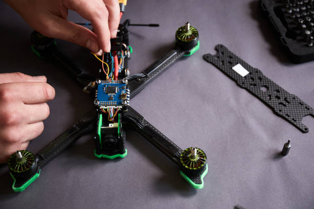istock Close up of man's hands assembling a drone from parts, using tools, Preparing high speed racing quadcopter for flight. Repair drone before training process. 1487040956
