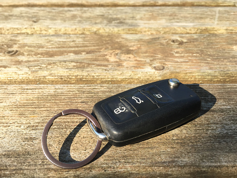 Car key on the outdoors wood table with sunlight reflection