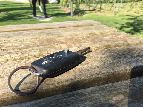 Car key on the outdoors wood table with sunlight reflection in garden