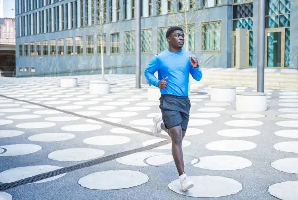 portrait of young sportsman running on white white spotted town square  in central berlin