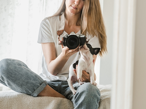 Cute puppy and a young woman with a camera. Clear, sunny day. Close-up, indoors. Studio photo. Day light. Concept of care, education, obedience training and raising pet