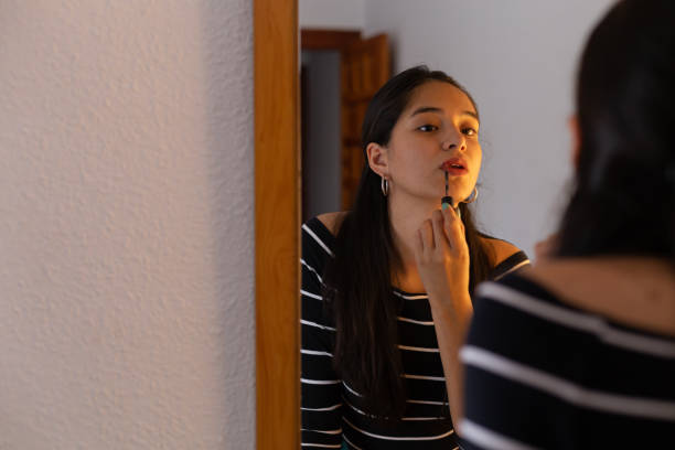 istock Young ethnic lady looking in mirror while applying mascara 1487049692