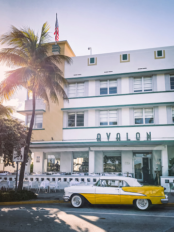 Miami, USA - August 31, 2022: View of a beautiful classic old American car from the 50s, at the doors of an art deco hotel on Ocean Drive, in Miami Beach, Florida.