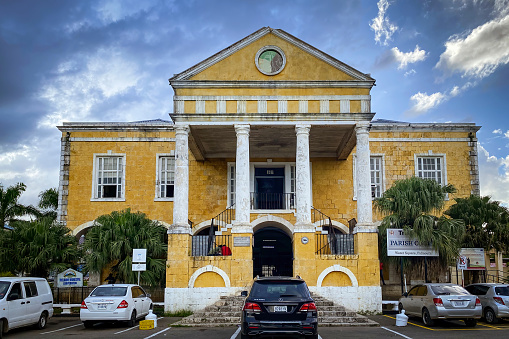 Falmouth, Jamaica  November 9, 2022: Yellow Court House building seen from Seaboard Street in the center of the town against blue sky with clouds