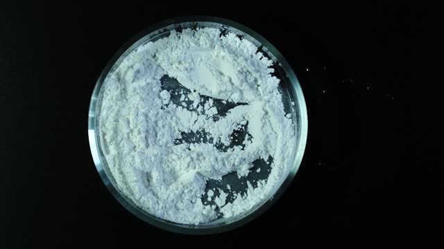 Titanium dioxide, TiO2 in Petri dish, top view. White chemical powder. Food additive E171. Titanium dioxide used in cosmetic and skin care products.