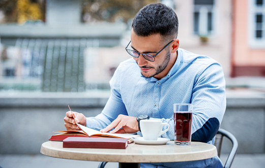 Young man sitting in a cafe and reading a book. Education, lifestyle concept