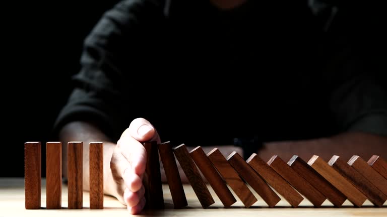 Risk Management Concept. Businessman hand stopping wooden domino business crisis effect or risk protection. Concept of Risk, Management, Assessment, Business, Crisis, Financial, Planning, Economic