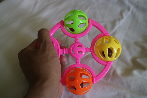 a photo of a colorful toddler toy that can make a tinkling sound with a pink handle