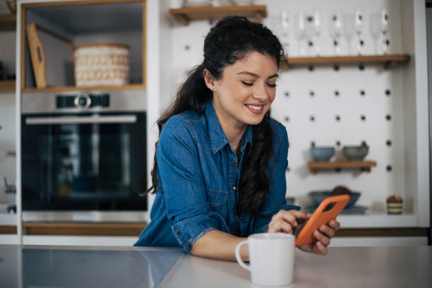 istock Beautiful woman in kitchen using phone 1487056728
